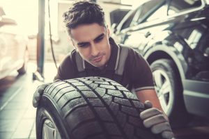 Handsome,Young,Auto,Mechanic,In,Uniform,Is,Examining,A,Tire